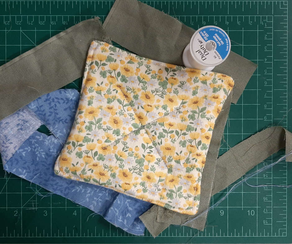 A coffee mug coaster made with sunflower patterned fabric. 